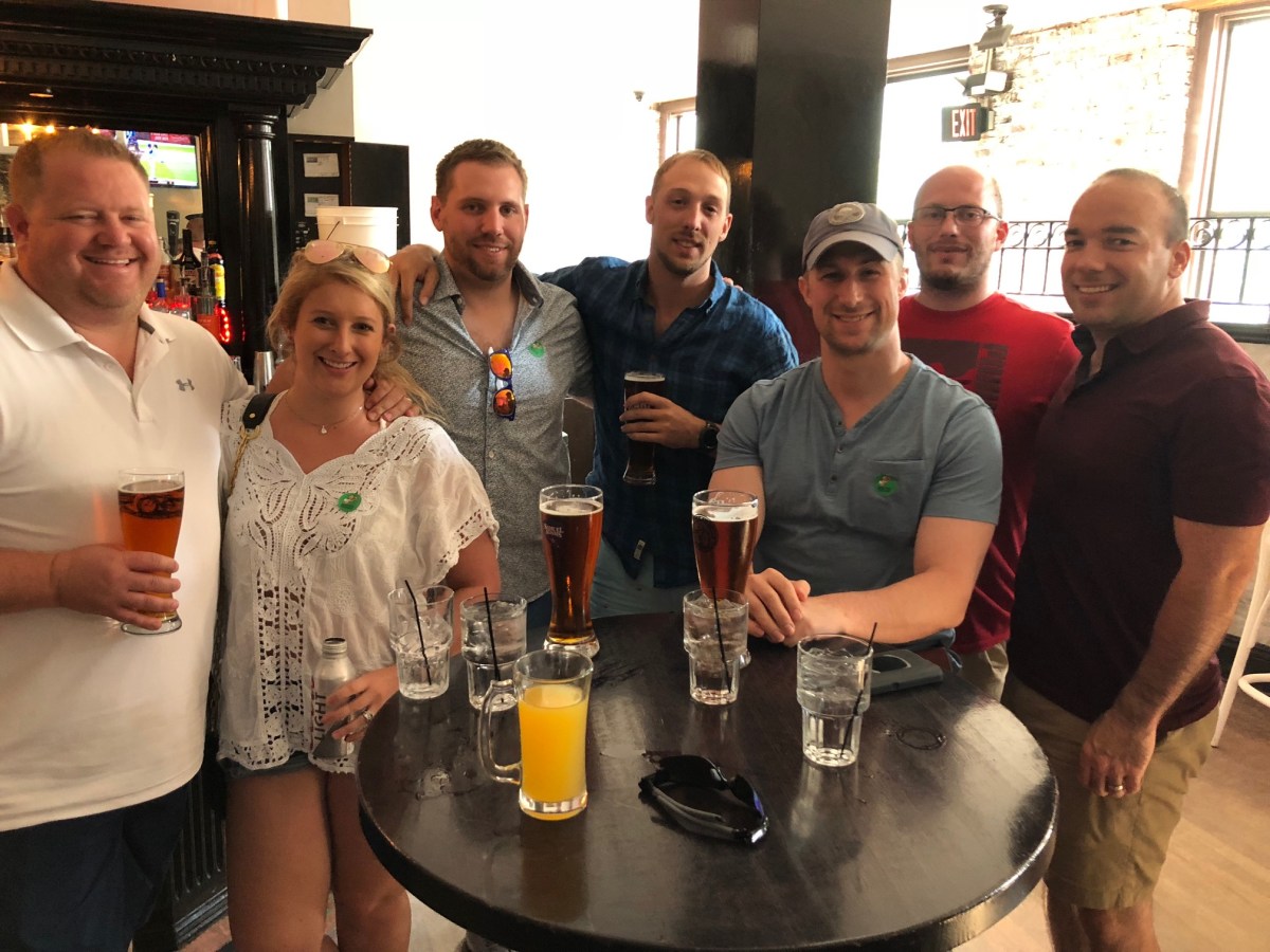 a group of people standing next to a bottle of wine