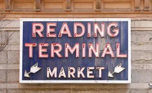 Sign reading 'Reading Terminal Market' with fish symbols on a building wall.